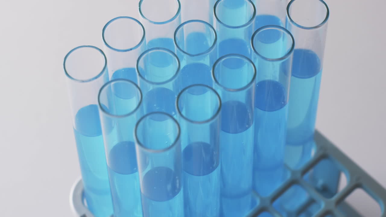 Video of glass laboratory test tubes with blue liquid with copy space on white background