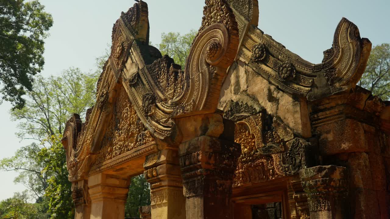 Ancient Banteay Srei Temple with intricate stone carvings in warm sunlight, Cambodia. Golden stone monumental archway to Khmer temple complex near the Cambodian city of Siem Reap and Angkor Watt