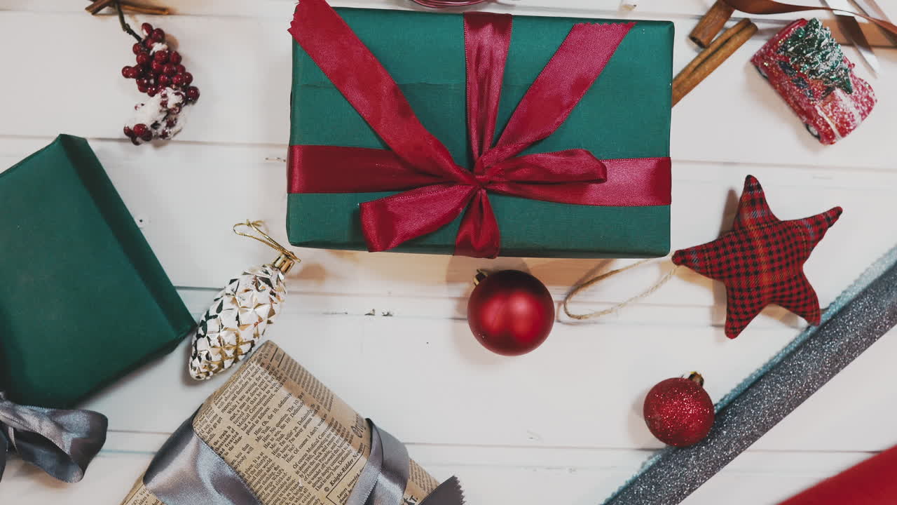 pasatiempo creativo. envoltorio de regalo. embalaje de modernas cajas de regalo de navidad en elegante papel gris con cinta roja satinada. vista superior de las manos sobre una mesa de madera blanca con ramas de abeto, decoración