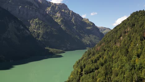 Majestic-Peaks,-Crystal-Waters:-Aerial-view-of-green-forest-and-Lakeside-Mountains