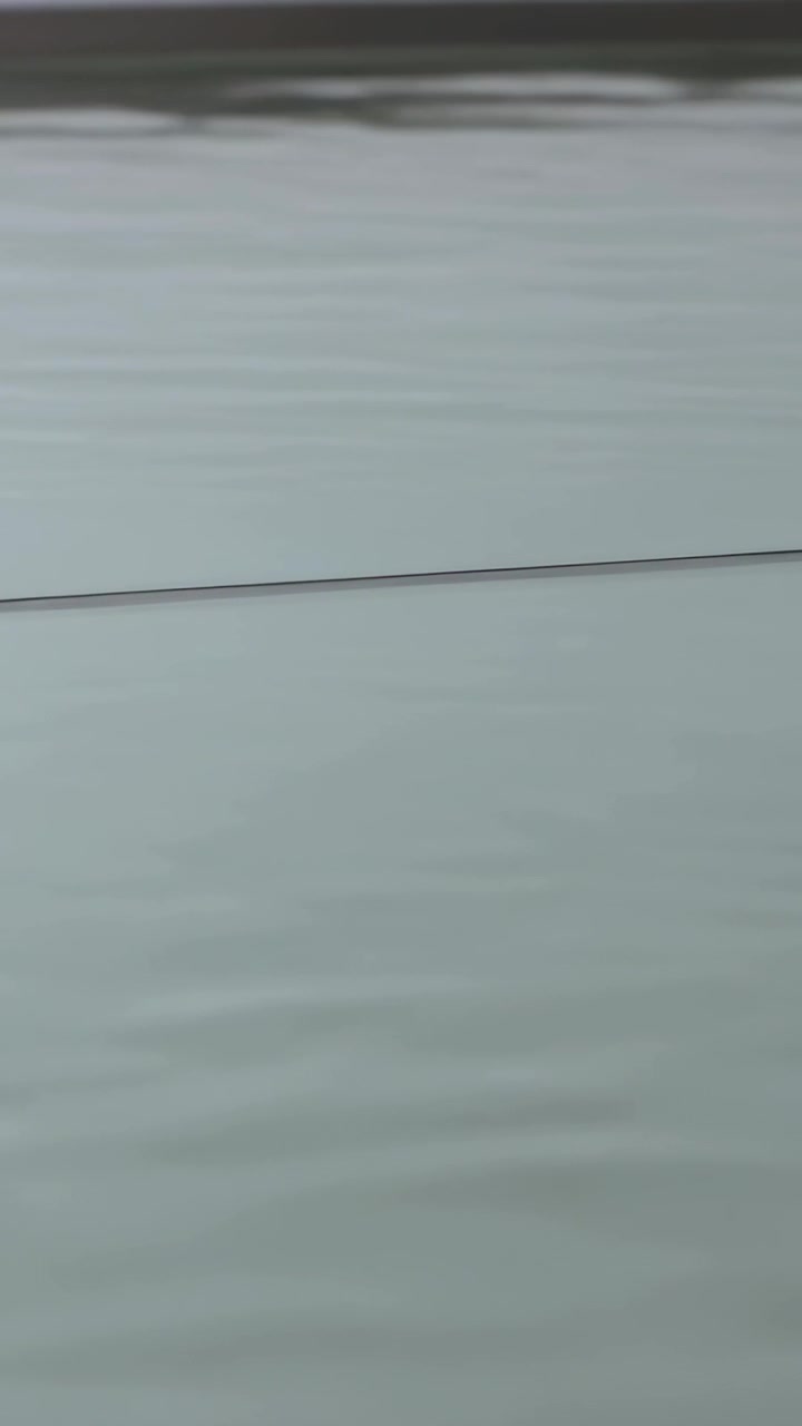 Vertical video: Tilting camera after still frames showing rippling water at dock with line and band