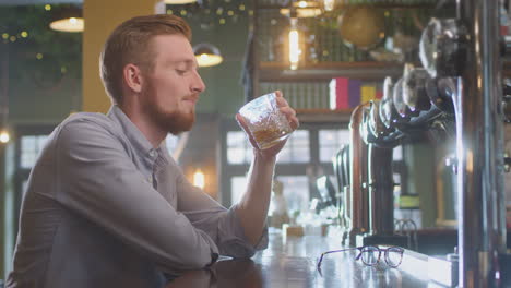 Unhappy-Man-Sitting-At-Pub-Bar-Drinking-Alone-With-Glass-Of-Whisky