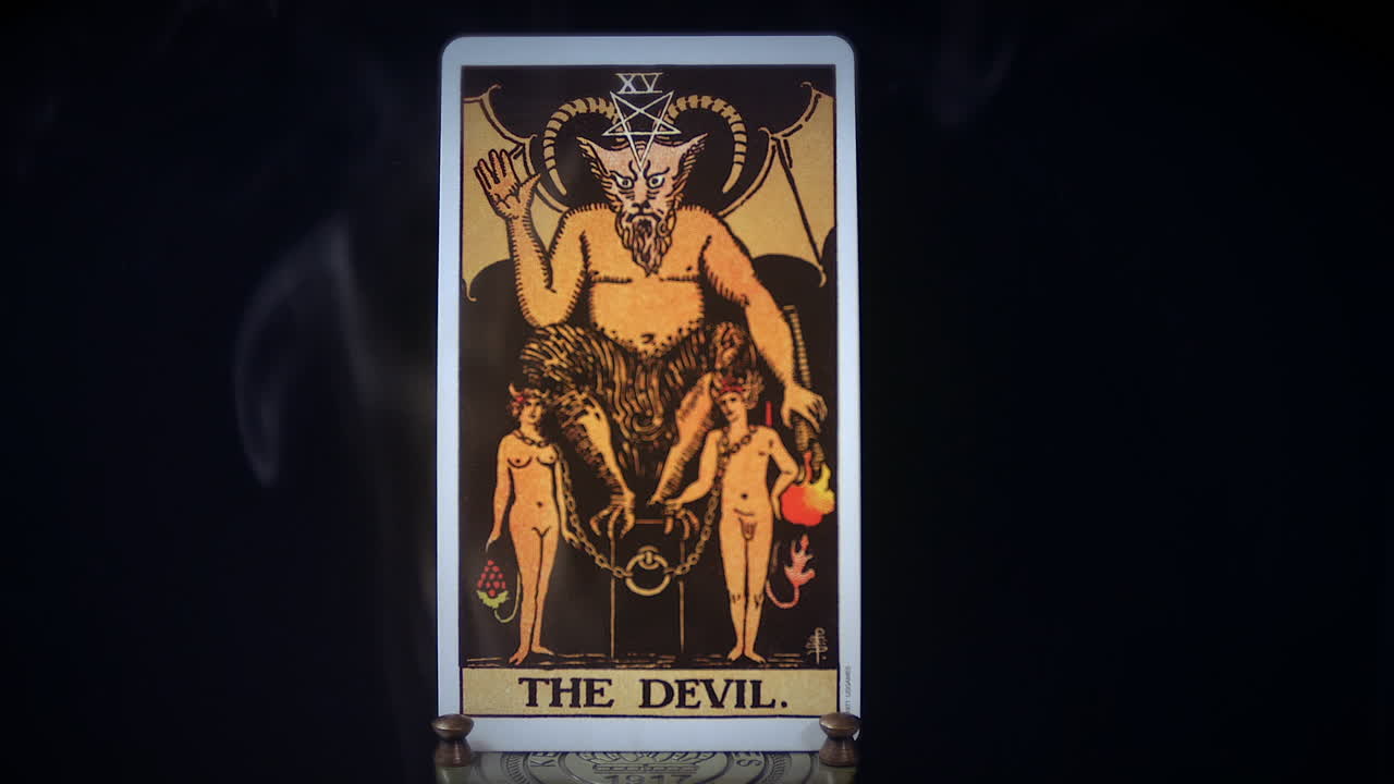 una carta del diablo del tarot se sienta en un soporte de latón mientras el humo se eleva a su alrededor