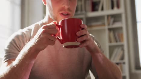 Caucasian-male-in-social-distancing-drinking-coffee-at-home