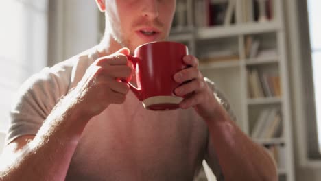 hombre caucásico en distanciamiento social bebiendo café en casa