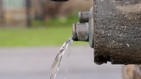 Young-man-with-beard-drinking-from-the-potable-water-spout-of-a-stone-fountain,-close-up-view,-outdoors-video