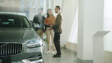 car salesperson discussing car with customers in showroom