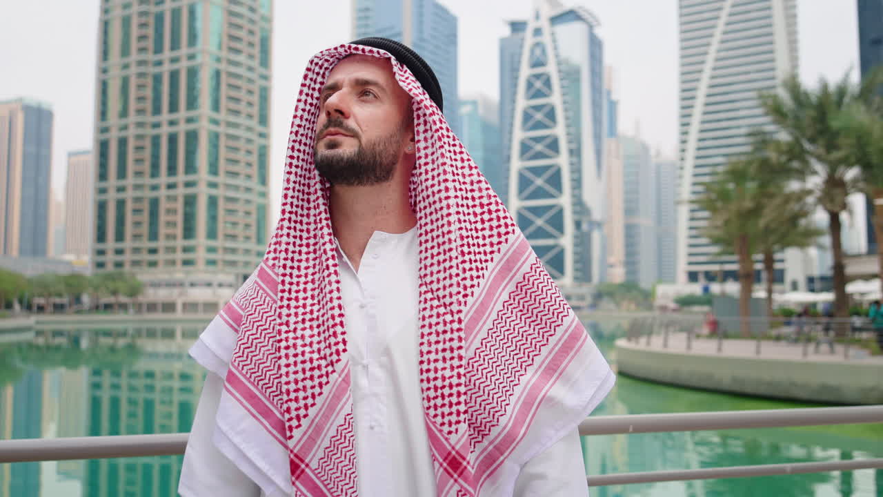 Un uomo d'affari arabo si erge solitario in una moderna area urbana, mostrando sicurezza e speranza per il futuro