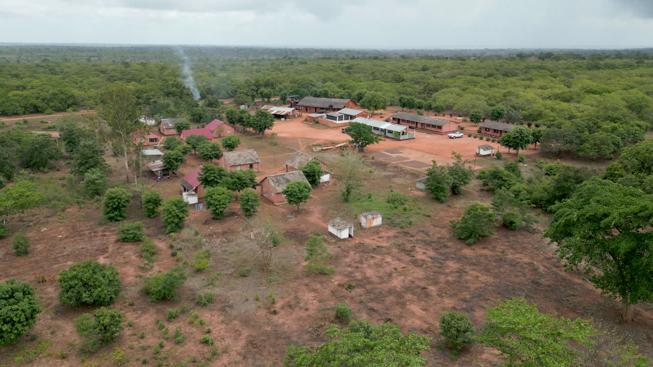 Simple African bush camp with mud buildings and small school surrounded by wild trees and vegetation in Northern Mozambique