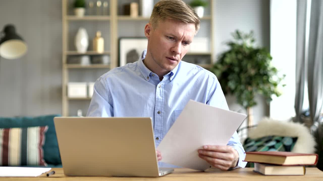 Businessman Reading Documents and Working on Laptop, Paperwork