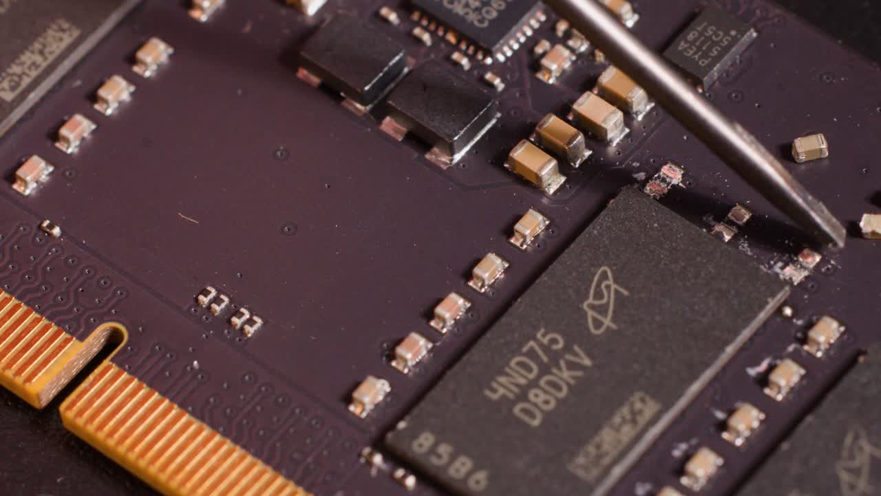 Close-up macro shot of a metal tool carefully inspecting components on a purple motherboard
