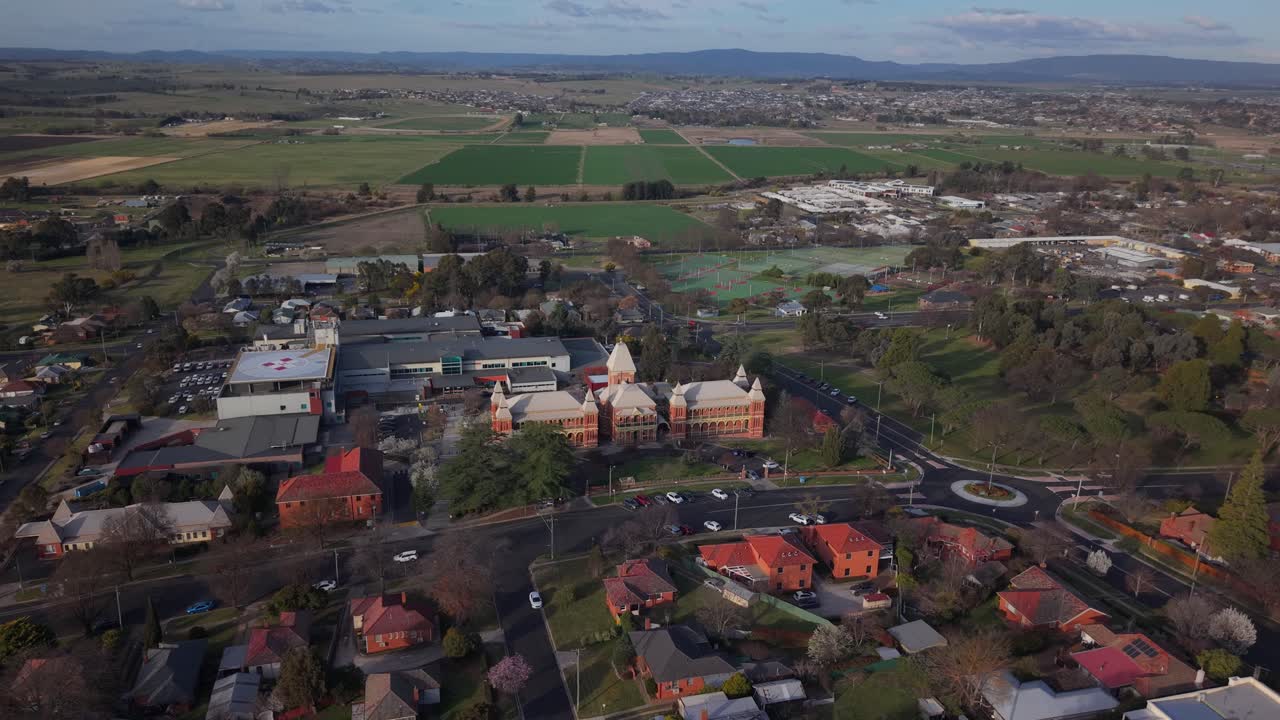 Overhead approach of Bathurst city blocks with hospital at center, long shadows cast by sunset