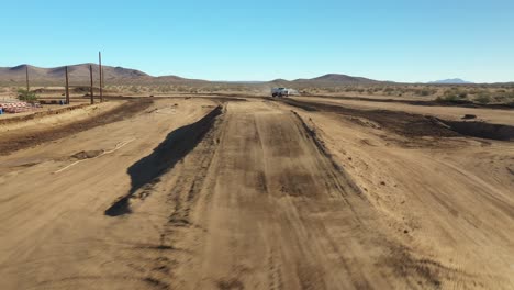 flying over a dirt motocross racetrack as a water truck sprays the dirt surface