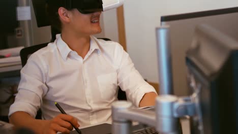 Graphic-designer-using-virtual-reality-headset-while-working-in-office