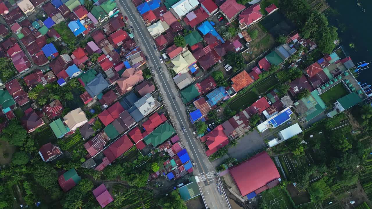 A top-view aerial of Talisay town with a central road cutting through colorful rooftops and forested edges in Batangas, Philippines