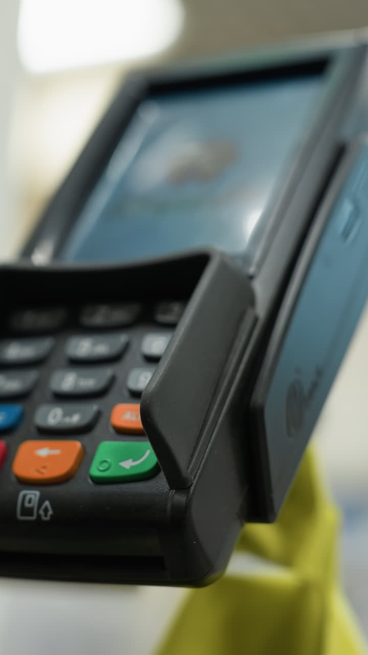 un primer plano de una mano con una pulsera de cuentas haciendo un pago con una tarjeta. el fondo está borroso, haciendo hincapié en el proceso de pago