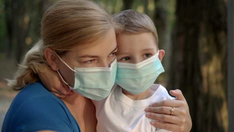 madre e hijo con máscaras médicas sentados en el parque