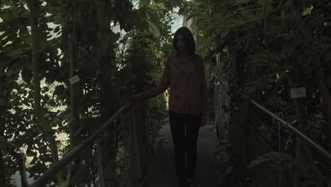 young woman walking through a beautiful botanical garden, wide shot, slow motion