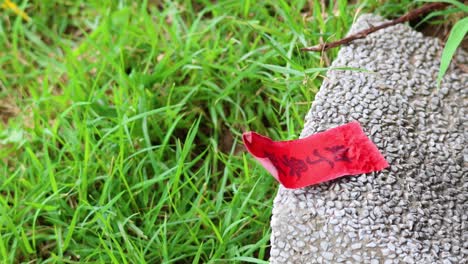 red paper flutters on a grave in the breeze