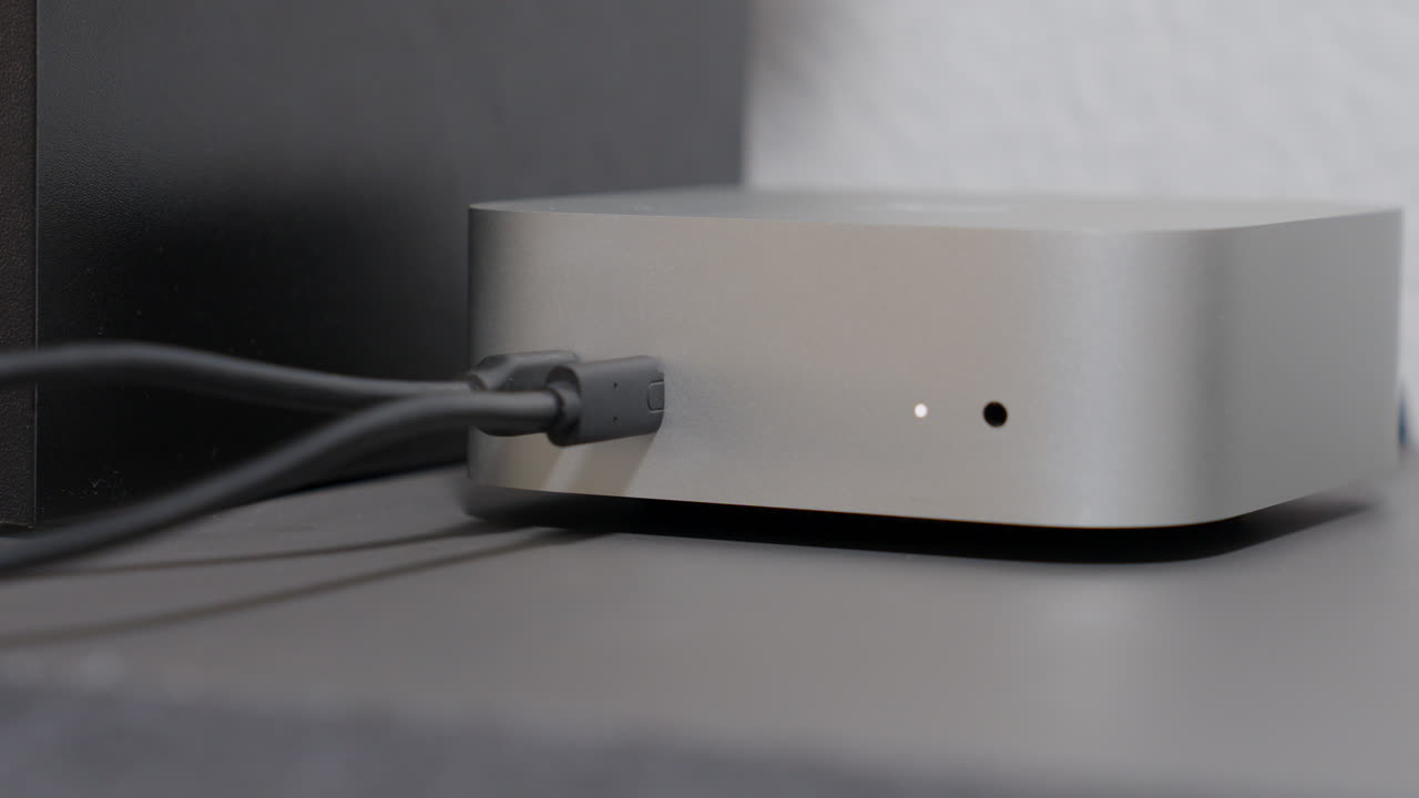 Close-up of a hand plugging a black usb-c cable into the port of a silver aluminum computer