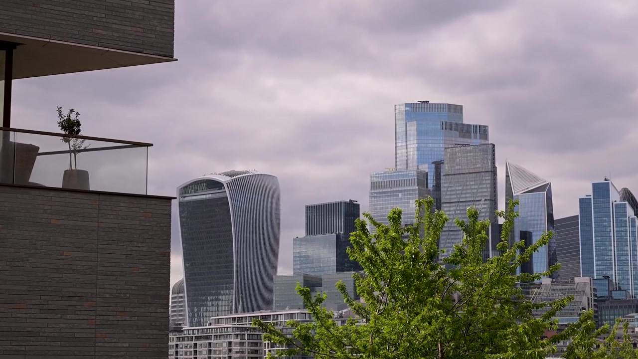 I grattacieli della City di Londra si ergono dietro gli appartamenti di Blenheim House, incorniciati da una vegetazione lussureggiante sotto un cielo nuvoloso. Adatto per temi di sviluppo urbano o per immagini immobiliari.