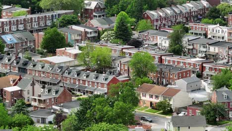 row of houses in american town during sunny day with green trees. aerial backwards shot. american classical townhouses in lancaster city, pennsylvania.