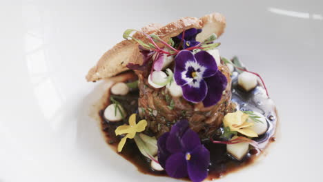 Prepared-and-decorated-meal-on-white-plate-in-kitchen,-slow-motion