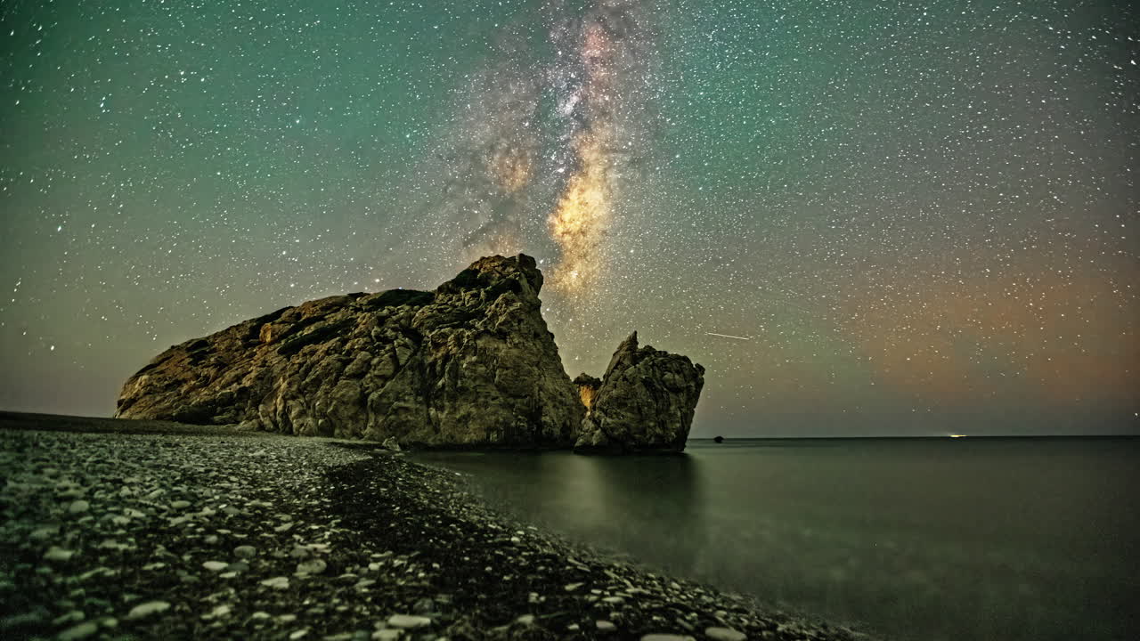 млечный путь проходит над скалой на береговой линии океана.