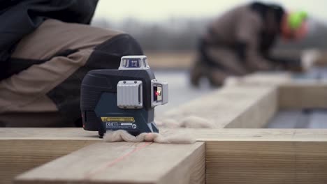 trabajadores de la construcción que utilizan el nivel láser en un proyecto de encuadre de techo