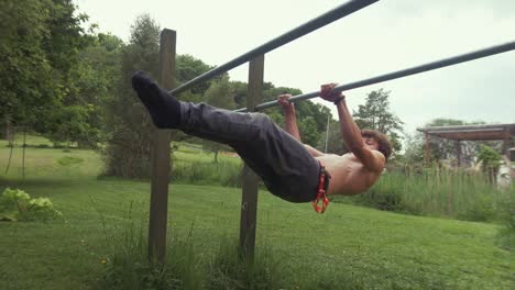 young fit male performs front lever exercise at outdoor home gym topless