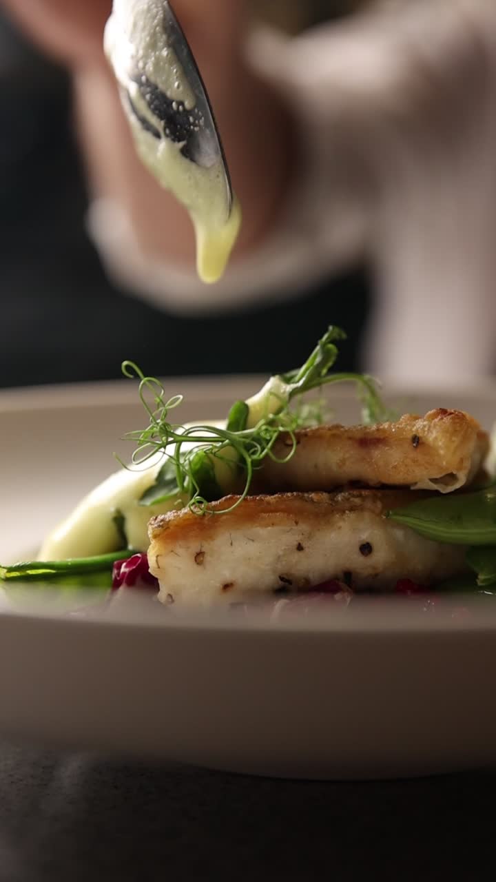 Chef Pouring Creamy Sauce Over a Gourmet Fish Dish
