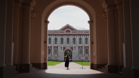 jelgava palace - woman tourist walking through arched gateway to the courtyard