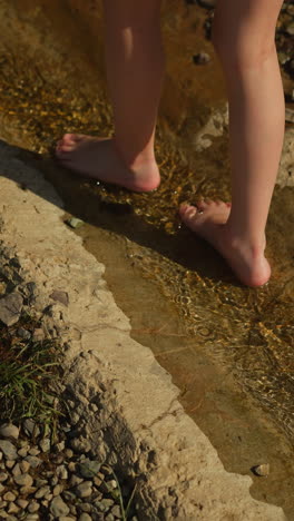 little girl feet walking alone in forest stream and enjoys nature. active child explores environment. recreation and awesome adventures with kid on warm summer day