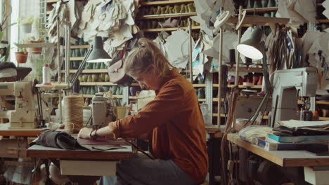 woman working with sewing machine in shoemakers workshop