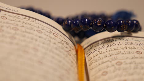 footage of a quran and a prayers bead near it, the shot is moving in a half circle