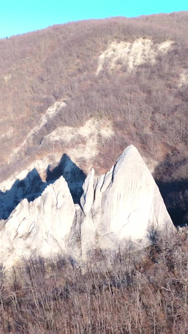 A cinematic aerial sweep over the sharp limestone spires of Salti del Diavolo in the Apennine Mountains, showcasing authentic nature and ecofriendly travel destinations.