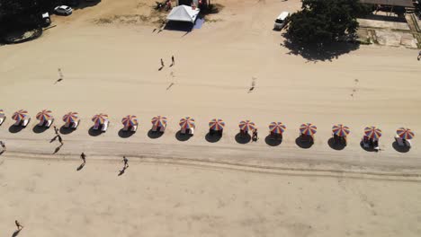 cámara lenta de arriba hacia abajo tiro de turistas en la playa con coloridos paraguas de playa