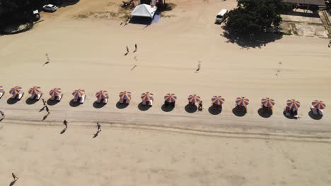 slow motion top down shot of tourists at the beach with colorful beach umbrellas