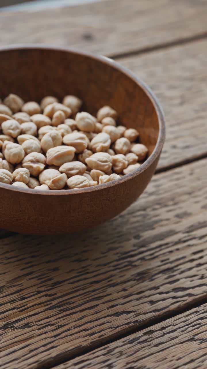 Close-up video angle of a wooden bowl filled with chickpeas on a rustic wooden table