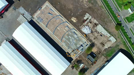 aerial view of a construction site with large white hangars and a new building under development