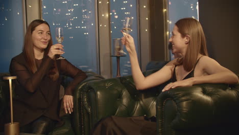 two women celebrating with champagne at a rooftop bar