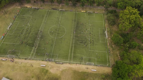 4k-60fps-Drohnenansicht-Von-Kindern,-Die-Fußball-Auf-Dem-Fußballplatz-Der-Schule-Trainieren