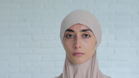 tranquil and sad emotion face expression on stunning muslim woman in hijab with the white background. a sad look looks into the camera with humility, the woman observes the rules of islam