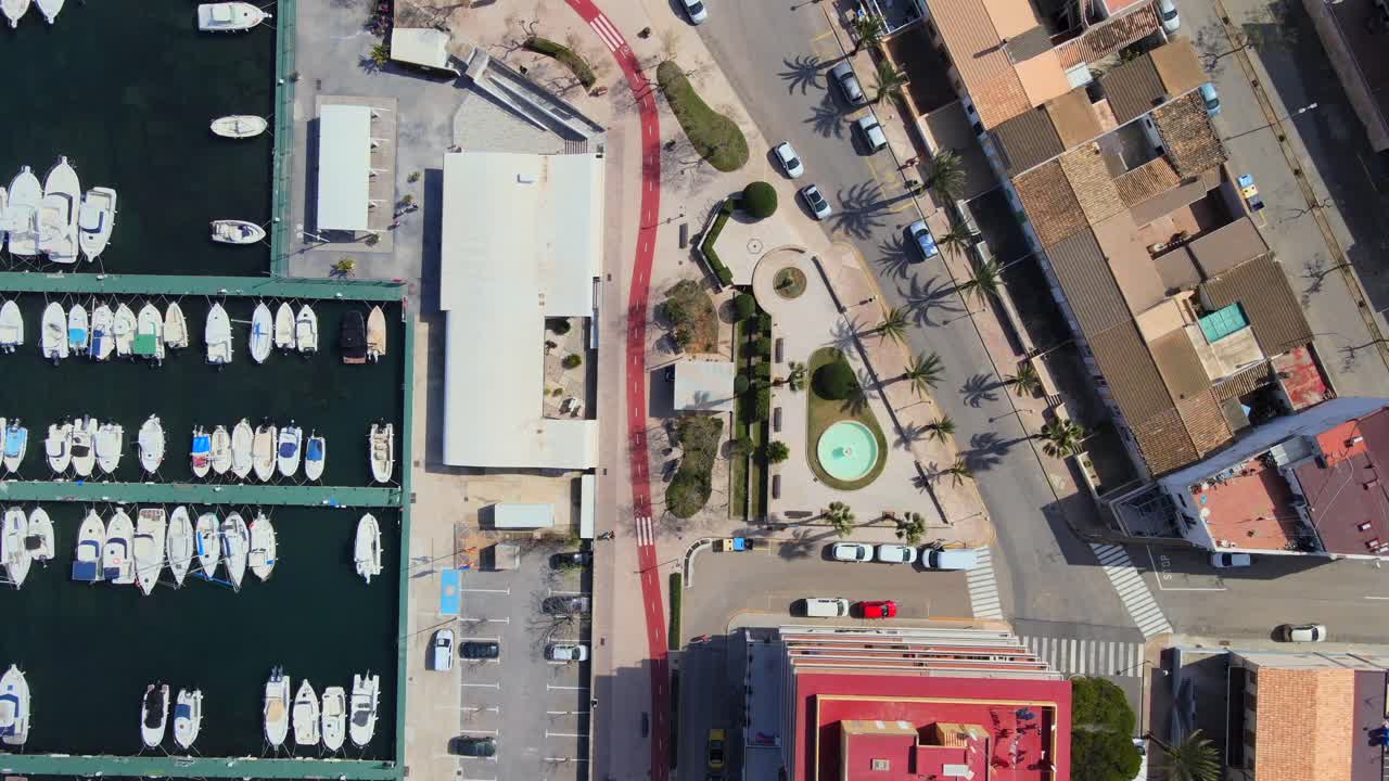 explore la impresionante vista aérea de can picafort y son baulo en mallorca, mostrando el puerto deportivo, los edificios cercanos, las palmeras y la vibrante atmósfera de la comunidad.