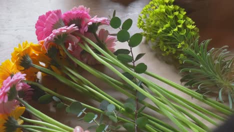 florist arranging a bouquet of gerbera transvaal daisies over shoulder view in slow motion 4k