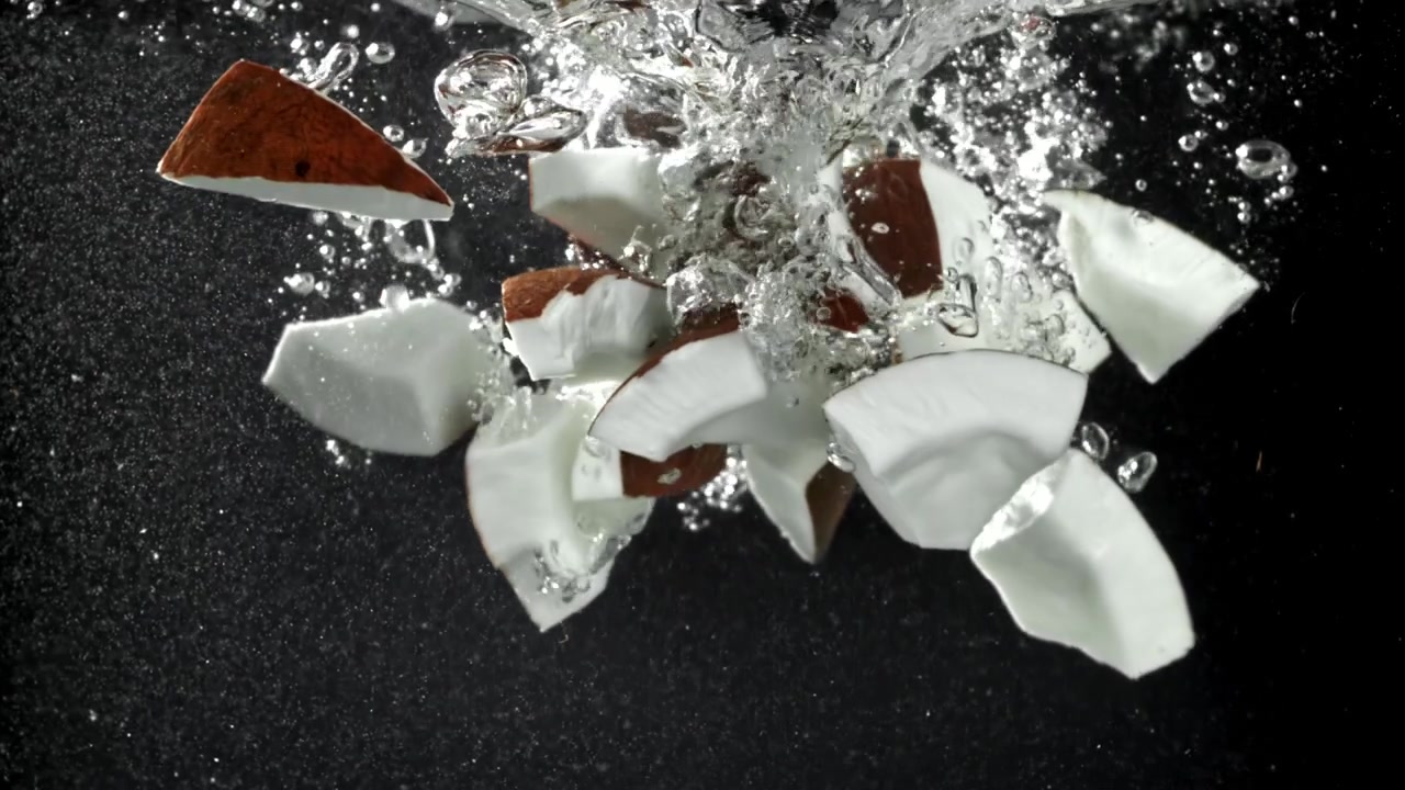 Pezzi di cocco che cadono in acqua limpida al rallentatore