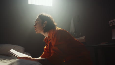 inmate reading bible and praying in sunlit prison cell