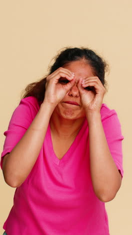 indian woman playfully forming glasses with fingers smiling cheerfully humorously looking camera
