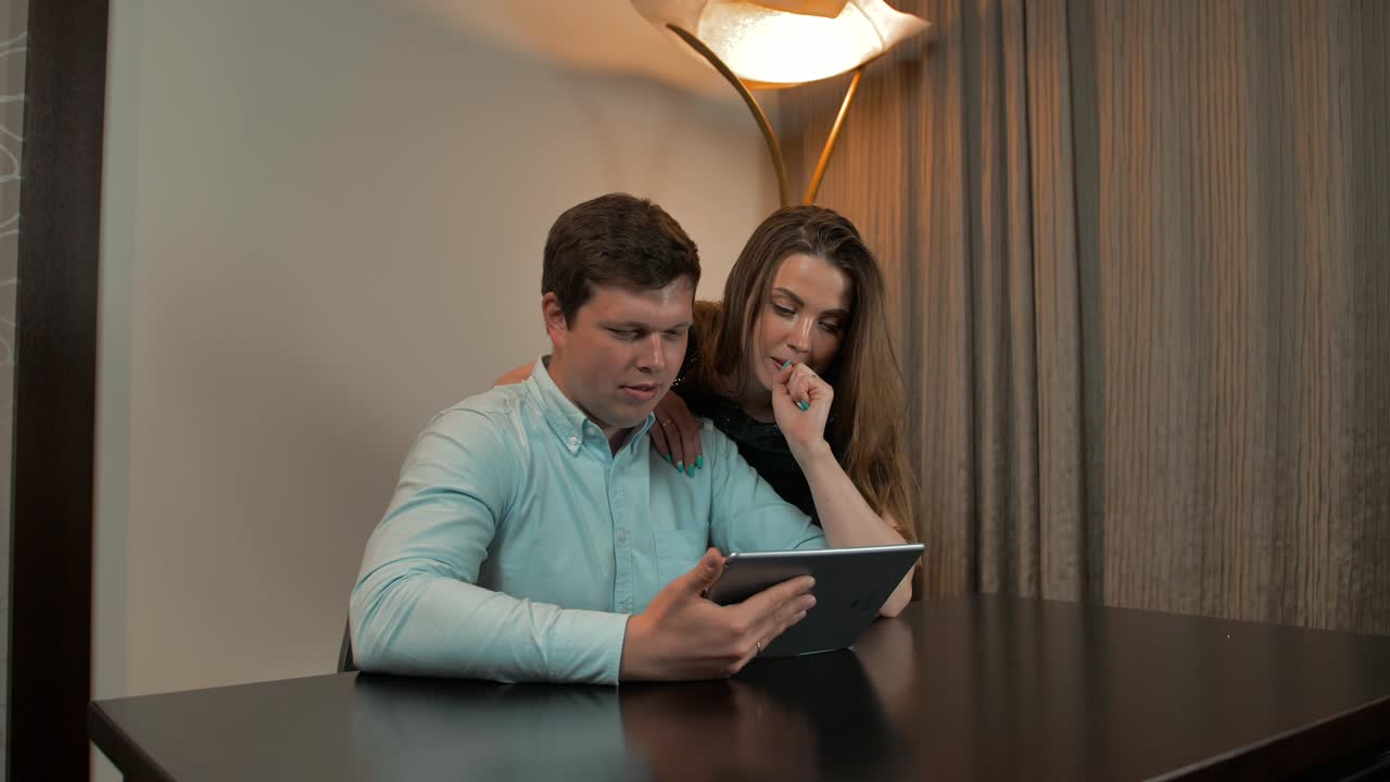 una pareja atractiva surfeando en una tableta digital en casa.