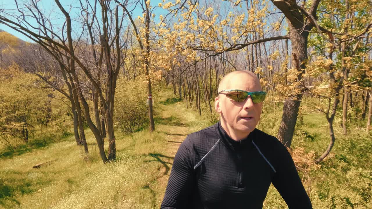 Vertical portrait orientation of a mature man jogging in nature. Seamless footage for mobile screens, Reels, and TikTok stories. Active lifestyle of seniors in their 50s